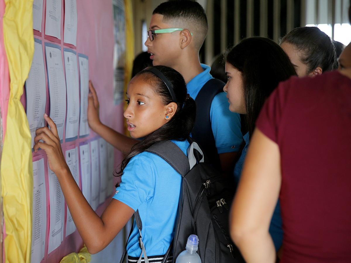 Students find their names and the numbers of the classrooms they are assigned to on lists posted in the lobby at Rosa Costa Valdivieso Middle School on Monday, Aug. 13, 2018. It was the first day of a new school year in Puerto Rico, almost a year after Hurricane Maria devastated the island.