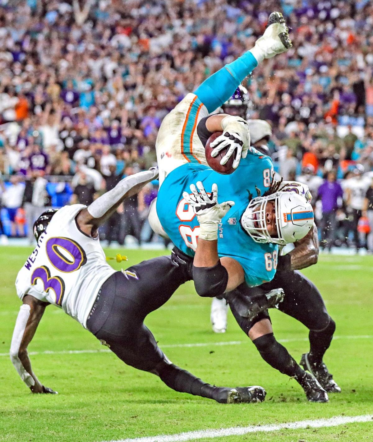 Miami Dolphins offensive lineman Robert Hunt (68), playing right guard, pulls a pass out of the air and rumbles to the end zone. Hunt cuts past one defender and gets hit low and flips through the air as he stretches the ball out, landing upside down on the goal line in the fourth quarter against the Baltimore Ravens at Hard Rock Stadium on Thursday, November 11, 2021. Technically, the play never happened, though. Officials called the play back for illegal touching. Hunt had not been declared eligible and therefore he could not be the first player to touch a pass thrown by the quarterback. Published November 12, 2021.