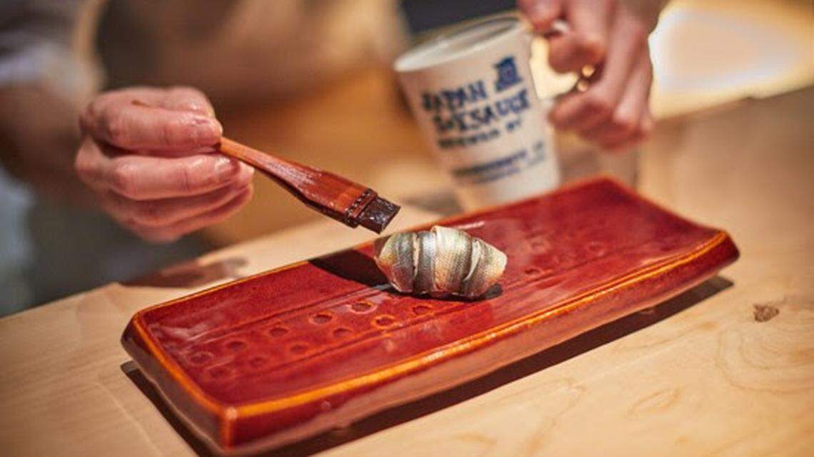 Chef Kevin Cory of Naoe swipes Naogen shoyu (soy sauce) on shinko nigirizushi on a plate by artist Toshio Ohi.