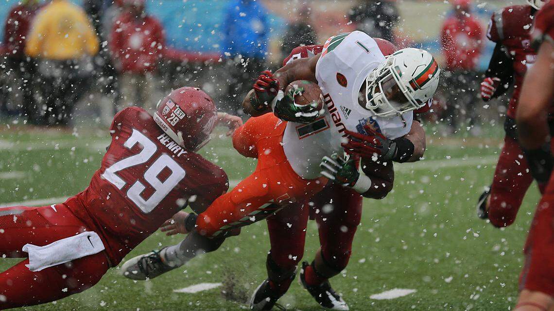 Miamis Mark Walton dives into the end zone to score a touchdown as snow falls during the fourth quarter of the Sun Bowl NCAA college football game Saturday, Dec. 26, 2015, in El Paso, Texas. Washington States Parker Henry, left, falls to the ground. (AP Photo/Victor Calzada)