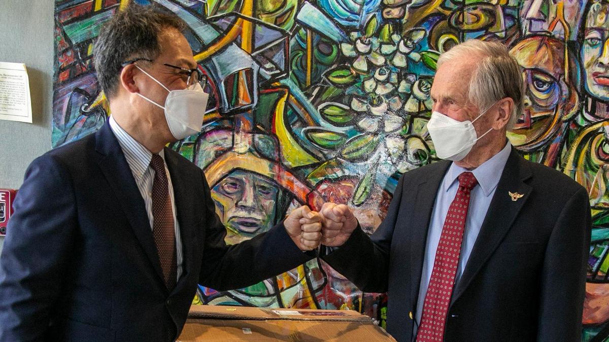 Burley Smith, right, fist-bumps Korean Consul General Young-jun Kim next to boxes containing masks that the government of Korea donated to the city of Miami during a small ceremony at Miami City Hall on Friday, January 22, 2021.