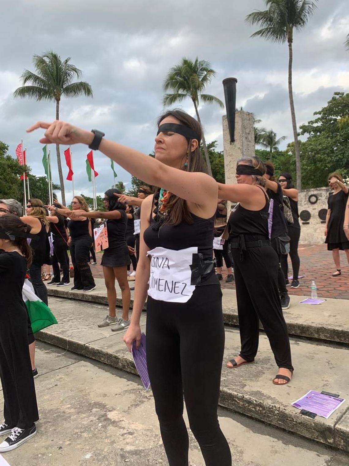 A woman points her index finger straight in front of her during the “Un violador en tu camino” or “A Rapist In Your Way” demonstration Sunday at the Torch of Friendship in downtown Miami. All women dressed in black, most wore black blindfolds and some wore signs with names of female victims on their chests.