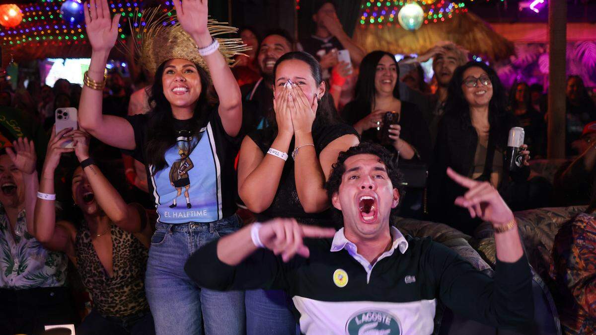 Bad Bunny fans - Kharina Caldera Soto, left, Yleinis Cardozo, and Tomas Calderaro, right, react as Bad Bunny starts his Half Time show. Casa Tiki held its “The Dead Flamingo Pop-Up” with the “Benito Bowl”, a Latin-themed Super Bowl party in honor of the Half Time Show by Bad Bunny on Sunday, February 8, 2026, in Miami, Florida.