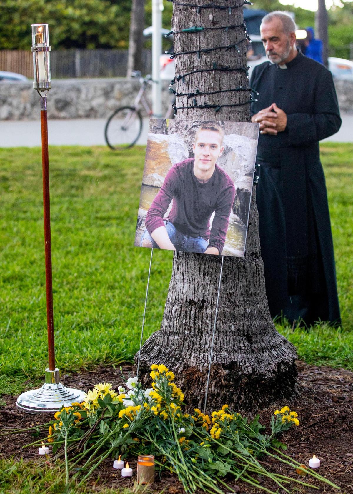 A priest stands behind a makeshift memorial during a vigil to honor the life of tourist Dustin Wakefield, at Lummus Park near Ocean Drive and 14th Street in Miami Beach, Florida, on Tuesday, August 31, 2021. Wakefield, 21, a tourist from Castle Rock, Colorado, was dining on Ocean Drive when he was shot multiple times.