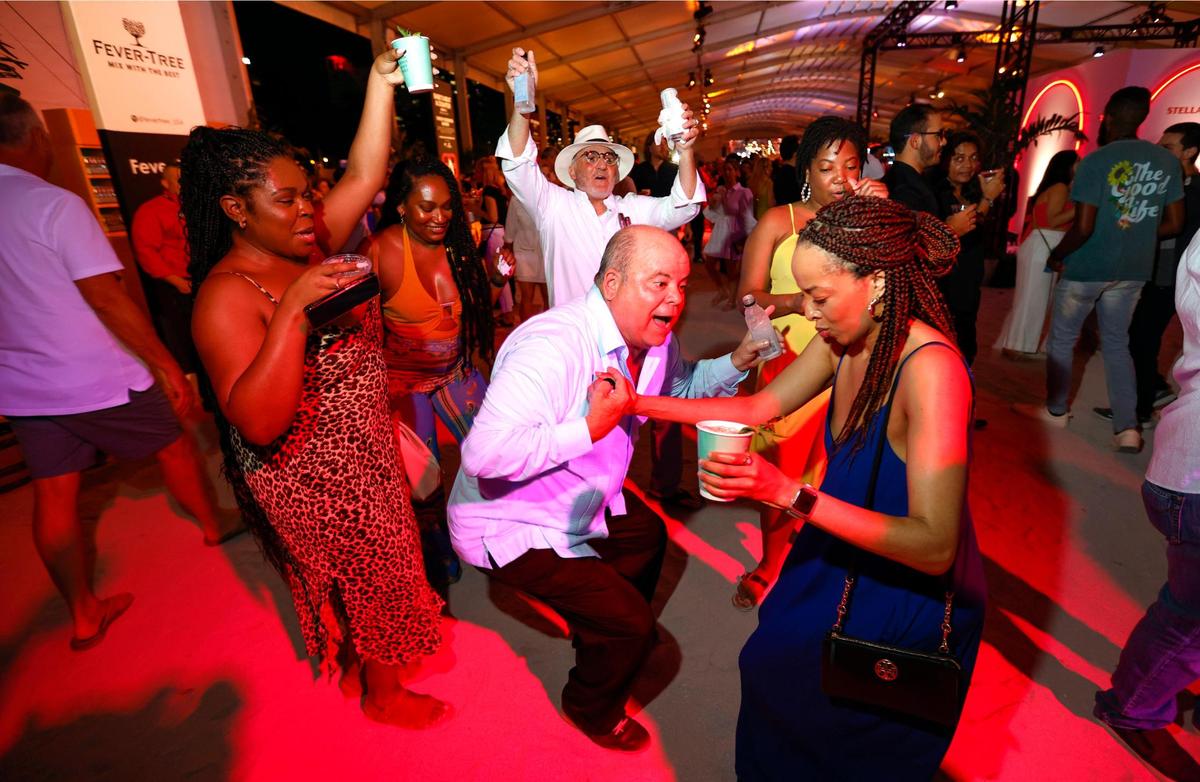 Evelio Medina and Jasmine Walker dance as others join in during the Burger Bash at the South Beach Wine & Food Festival on the sand by the Ritz Carlton in Miami Beach, Florida on Thursday, February 23, 2023.