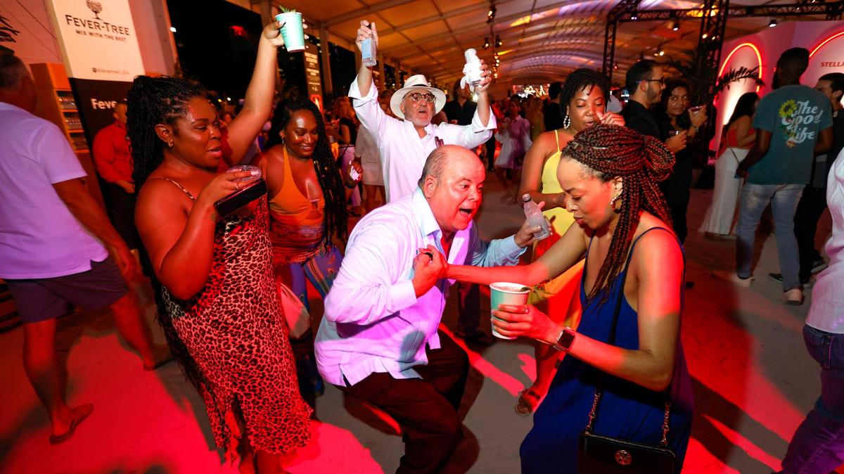 Evelio Medina and Jasmine Walker dance as others join in during the Burger Bash at the South Beach Wine & Food Festival on the sand by the Ritz Carlton in Miami Beach, Florida on Thursday, February 23, 2023.