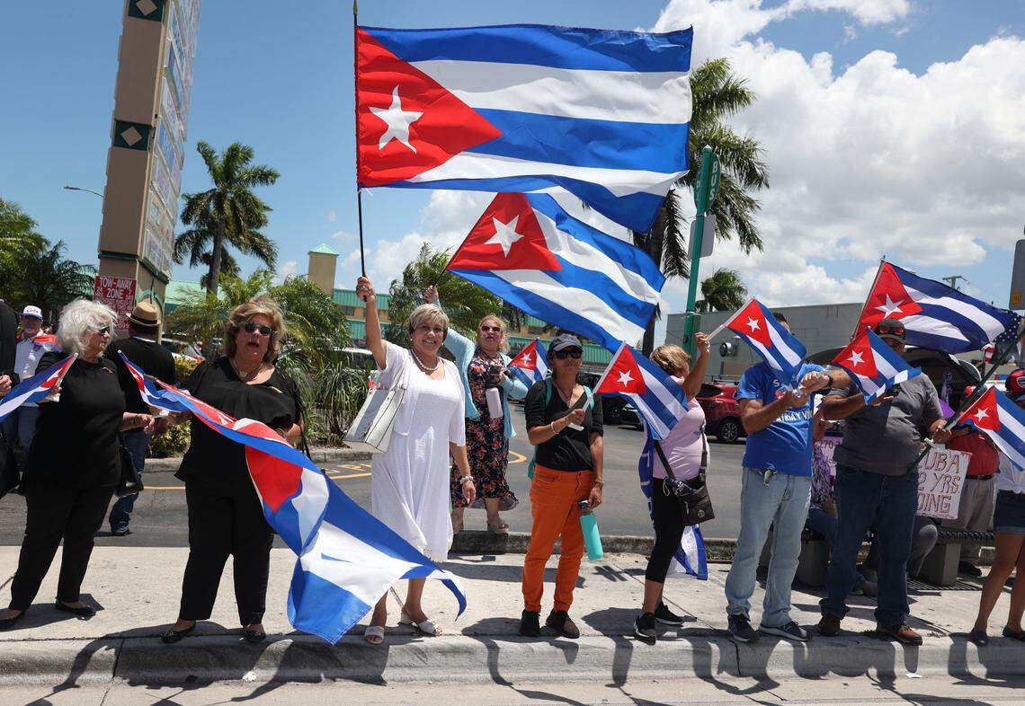 Cristina Maria Rodriguez Penton, 59, center, white dress, from Cuba on a church exchange program, waves a flag during a Cuban flag distribution along SW 40th Street on Monday, July 11, 2022 outside of La Carreta on Bird Road. The Assembly of the Cuban Resistance held a series of activities to commemorate the first anniversary of the July 11 mass protests in Cuba.