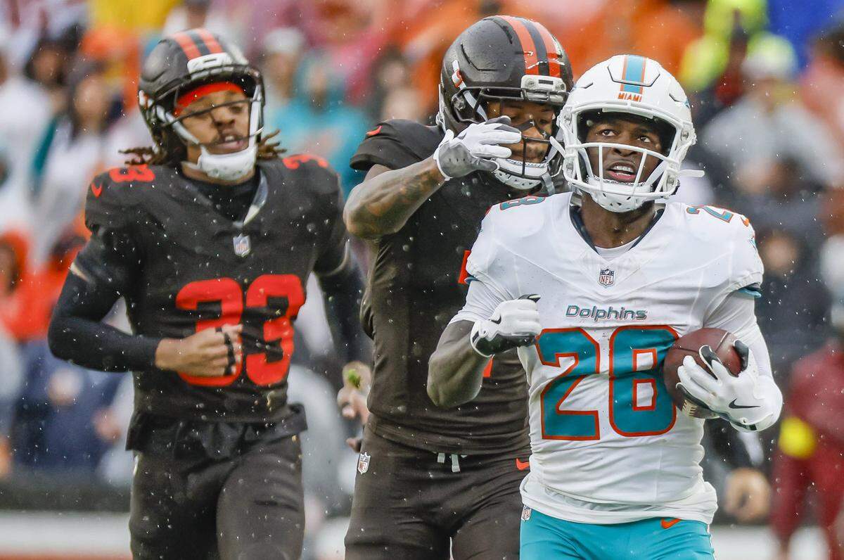 Miami Dolphins running back De'Von Achane (28) runs the ball as Cleveland Browns Tysen Brown (7) gives chase for the tackle during the first half of an NFL football game at Huntington Bank Field in Cleveland, Ohio, on Sunday, October 19, 2025.
