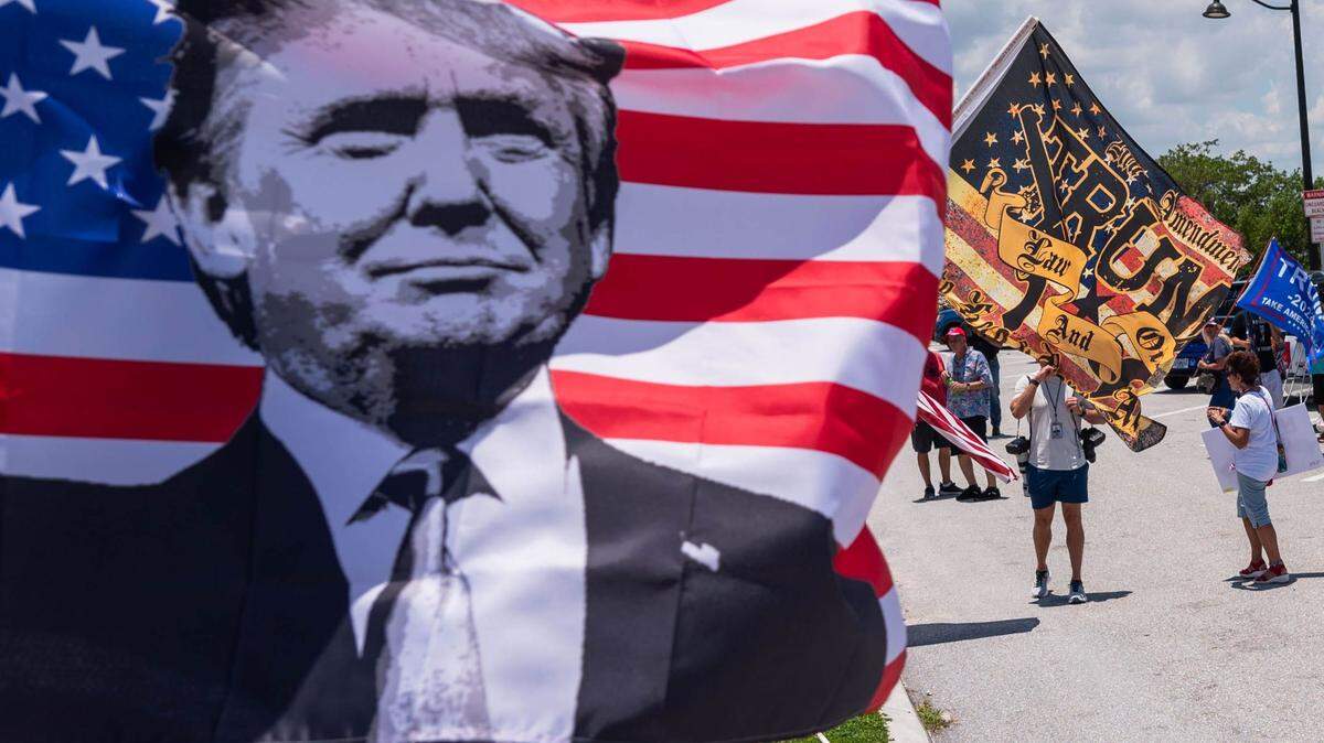 Simpatizantes del ex presidente Donald Trump ondeando banderas durante un acto el 11 de junio en West Palm Beach.