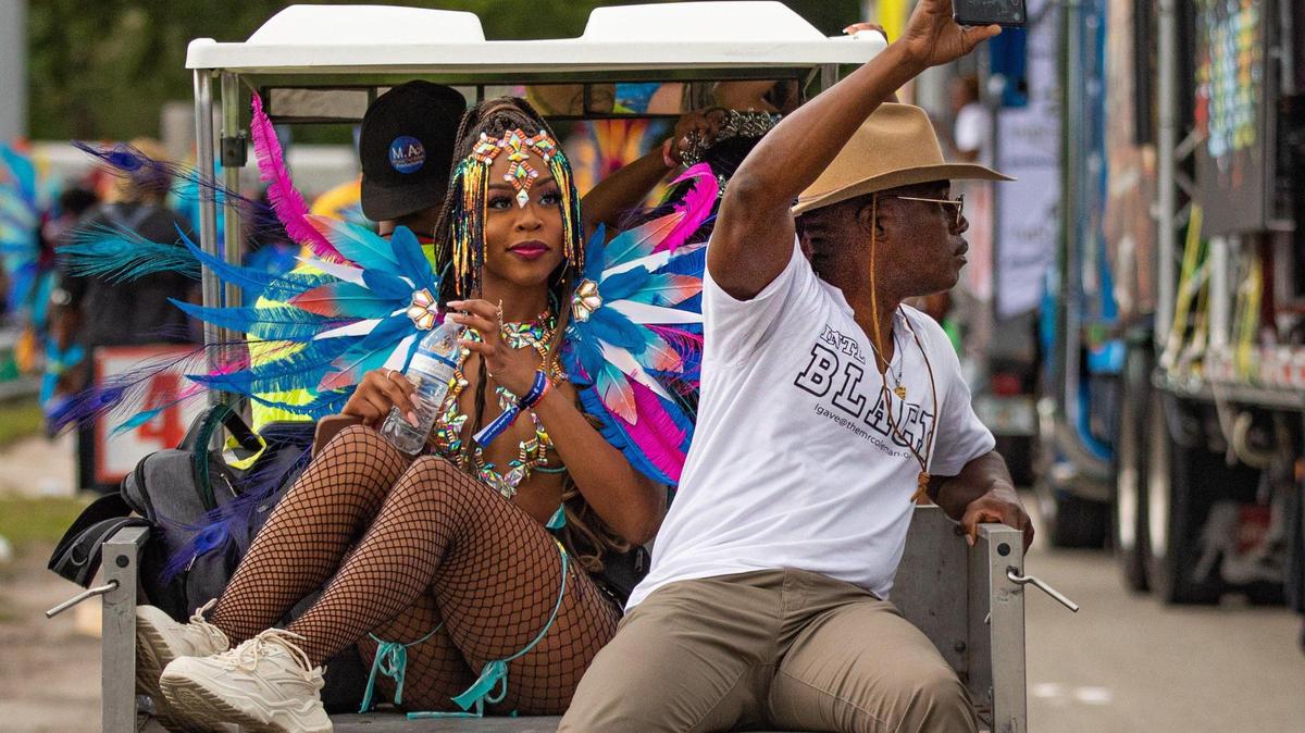 A performer rides on the back of a golf cart during Miami Carnival at the Miami-Dade County Fair Expo in Miami, Florida on Sunday, October 9, 2022. A foot injury from a golf cart could be serious.