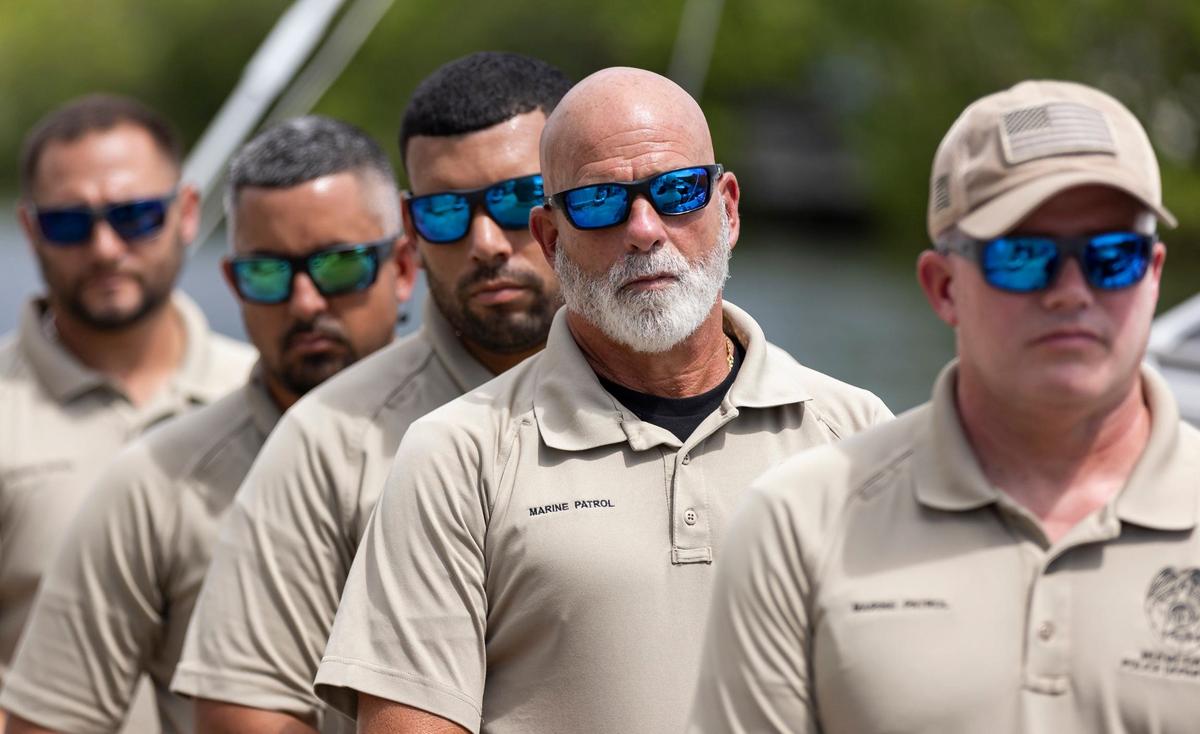 Officer Thomas Kennedy, center, with the Miami-Dade Marine Patrol Unit, watches as Melissa Fernandez presents Fly High, Bird flags to his unit at the Black Point Park and Marina on Friday, Aug. 30, 2024, in Homestead, Fla. Fernandez, who started the Lucy Fernandez Foundation with her husband after their daughter was killed in a boat crash two years ago, hopes the flags that will hang on Miami-Dade Police vessels will raise awareness of boat safety.