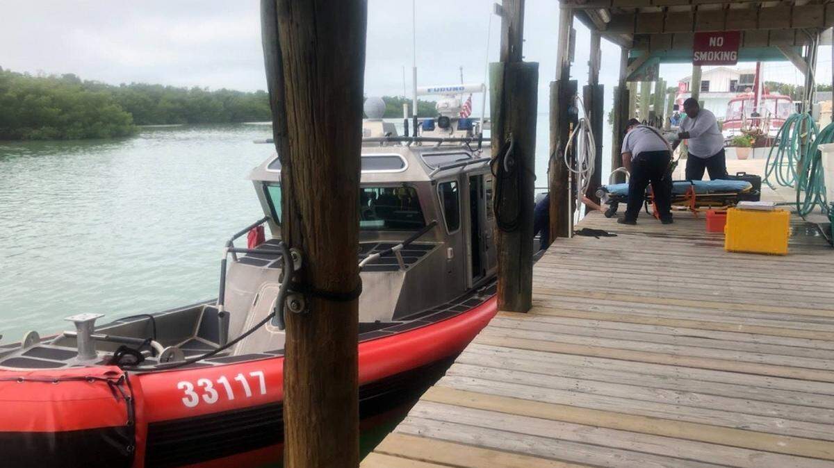 Emergency Medical Services technicians with Marathon Fire Rescue prepare to receive a woman rescued from a sailing vessel six miles east off Boot Harbor by U.S. Coast Guard Station Marathon crewmembers. A 33-foot Special Purpose Law Enforcement boat crew transported the woman to Burdines Marina for further medical assistance.