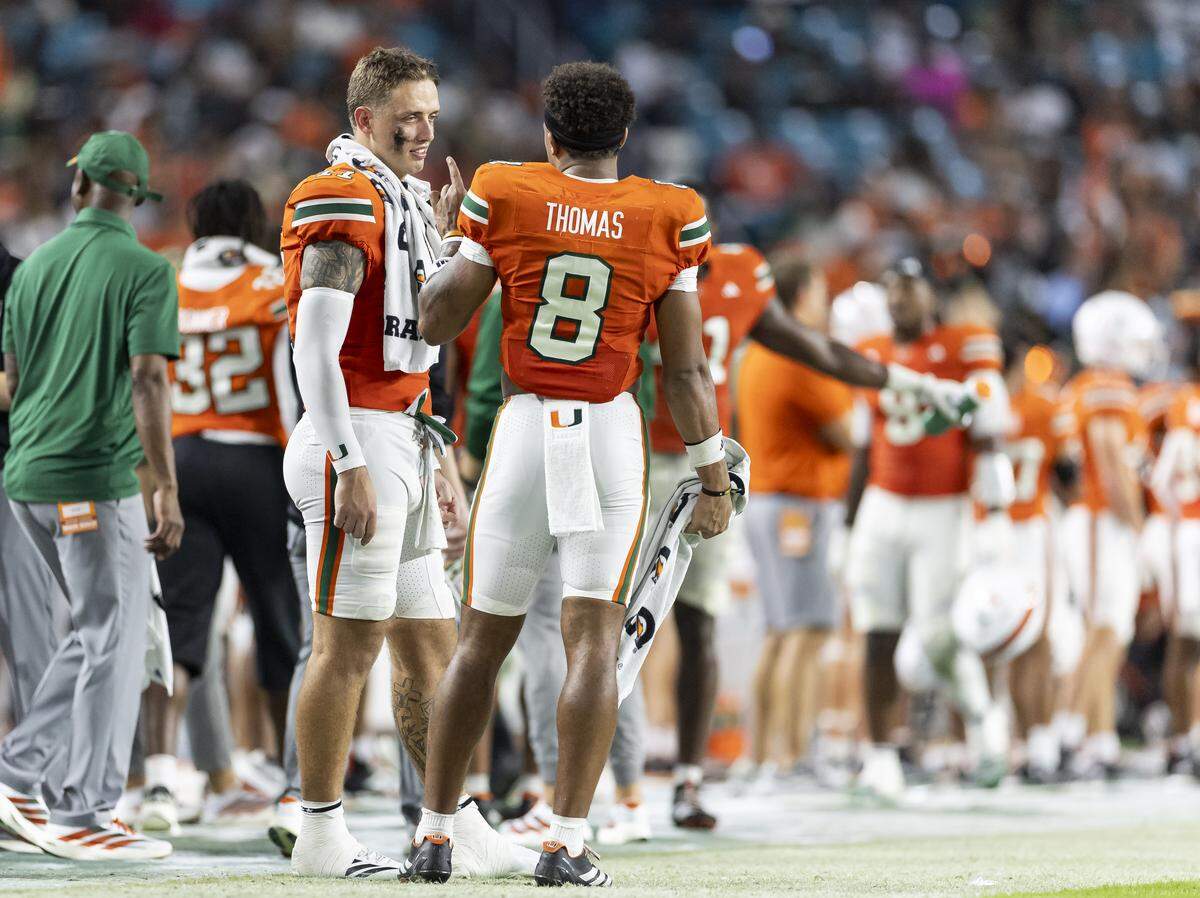 Miami Hurricanes quarterbacks Carson Beck (11) and defensive back Jakobe Thomas (8) talk on the sideline as their team plays against Bethune-Cookman Wildcats in the second half of their NCAA football game at Hard Rock Stadium on Saturday, Sept. 6, 2025, in Miami Gardens, Fla.