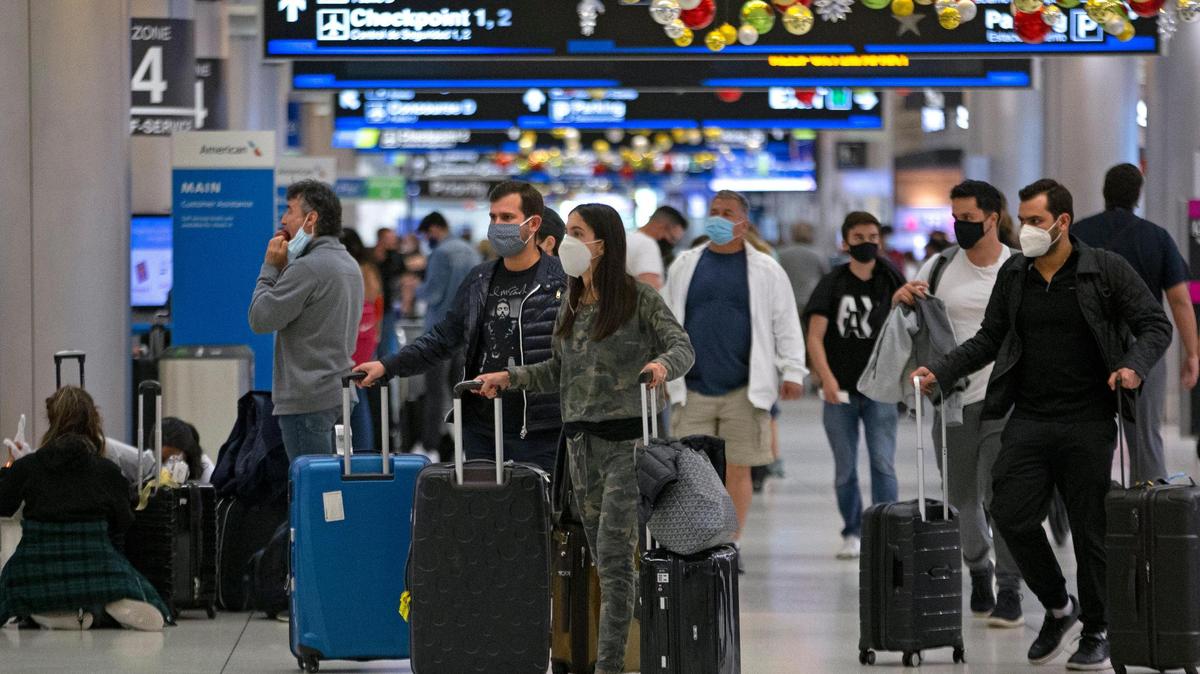 Travelers wearing protective face masks walk through Concourse D at Miami International Airport in 2020.