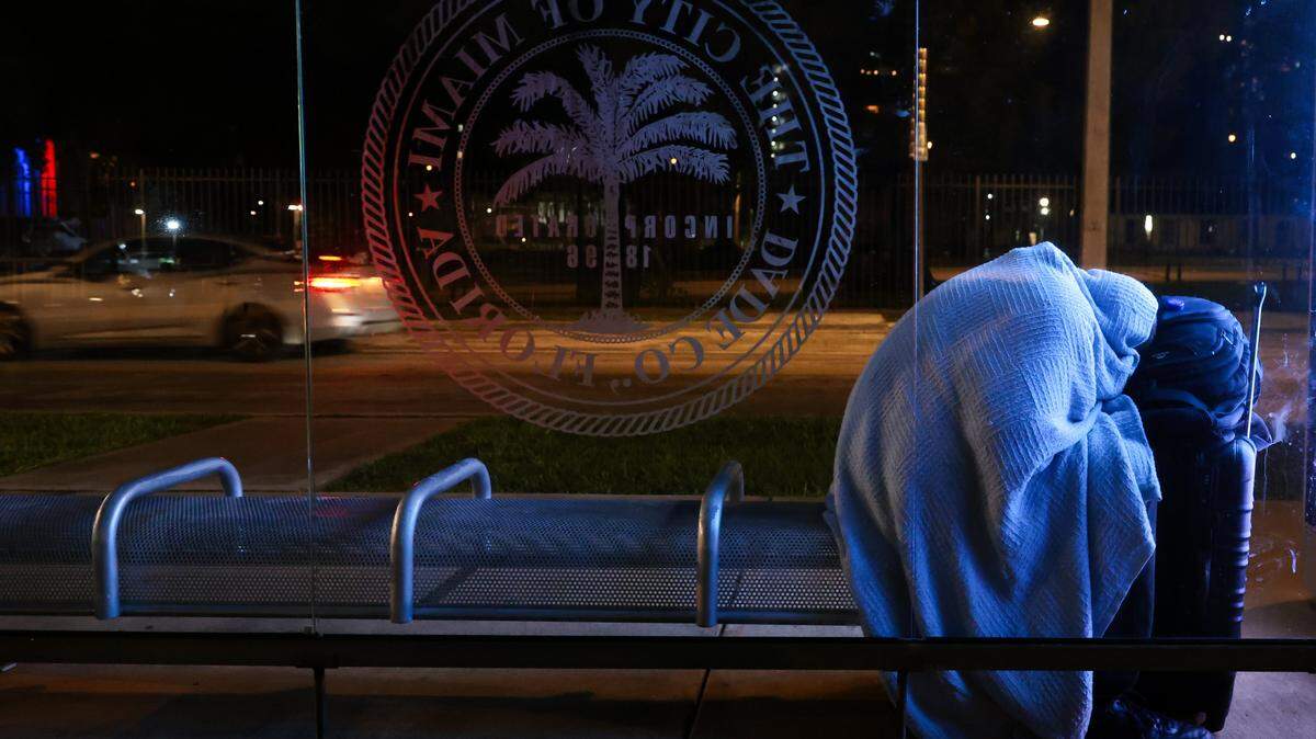 A man experiencing homelessness sleeps at a bus stop near Lummus Park in downtown Miami during the Homeless Trust's biannual Homeless Census on Thursday, Jan. 22, 2026.
