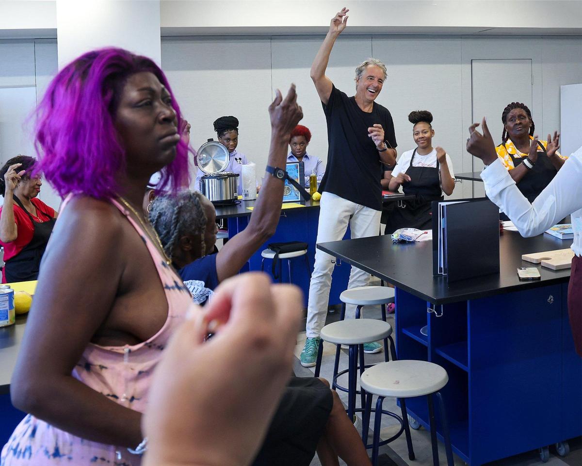 Miami Beach resident Dan Buettner, center, host and co-producer of Netflix’s Emmy Award-winning series “Live to 100: Secrets of the Blue Zones,” joins in snapping as the group of women gave their applause during an icebreaker at the start of their Blue Zones cooking class on April 3, 2025, in Miami, Florida.