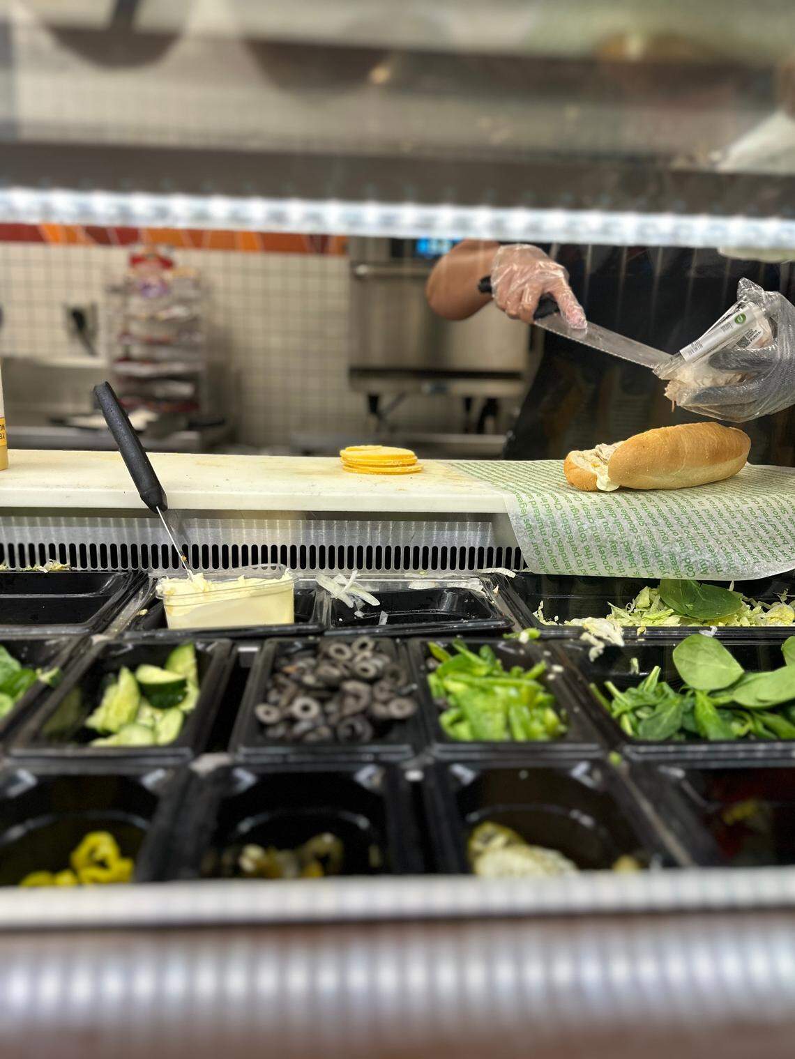 A Publix deli staffer spreads tuna inside a new soft white roll for one of the supermarket chains popular Pub Subs at the Palms at Town & Country store on Feb. 14, 2025.