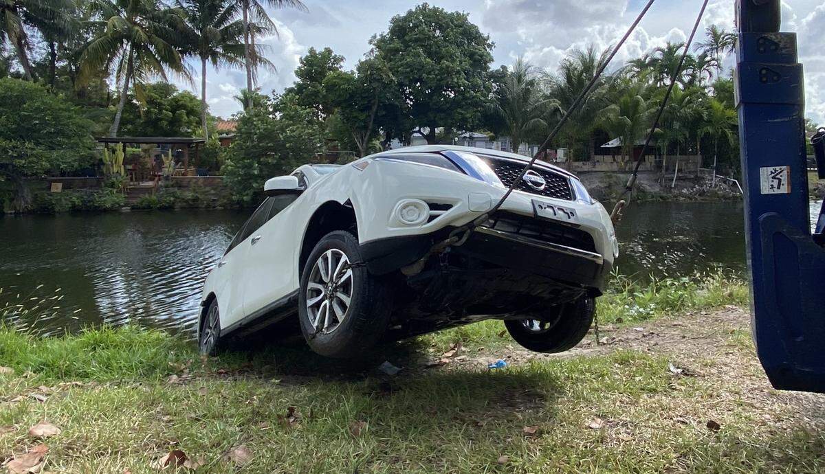 A stolen white Nissan Pathfinder is towed out of a canal at Northwest 154th Street and Second Avenue on Monday afternoon, May 31, 2021. Miami-Dade County police say gunmen used the vehicle in a May 30 shooting that left two dead and 21 wounded.