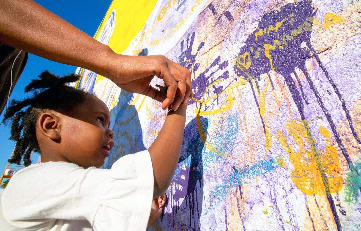 Malaysia Saintcyr, 3, paints a message on a mural dedicated to Kobe Bryant and his daughter Gianna in Miami’s historic Overtown community on Feb. 3, 2020.