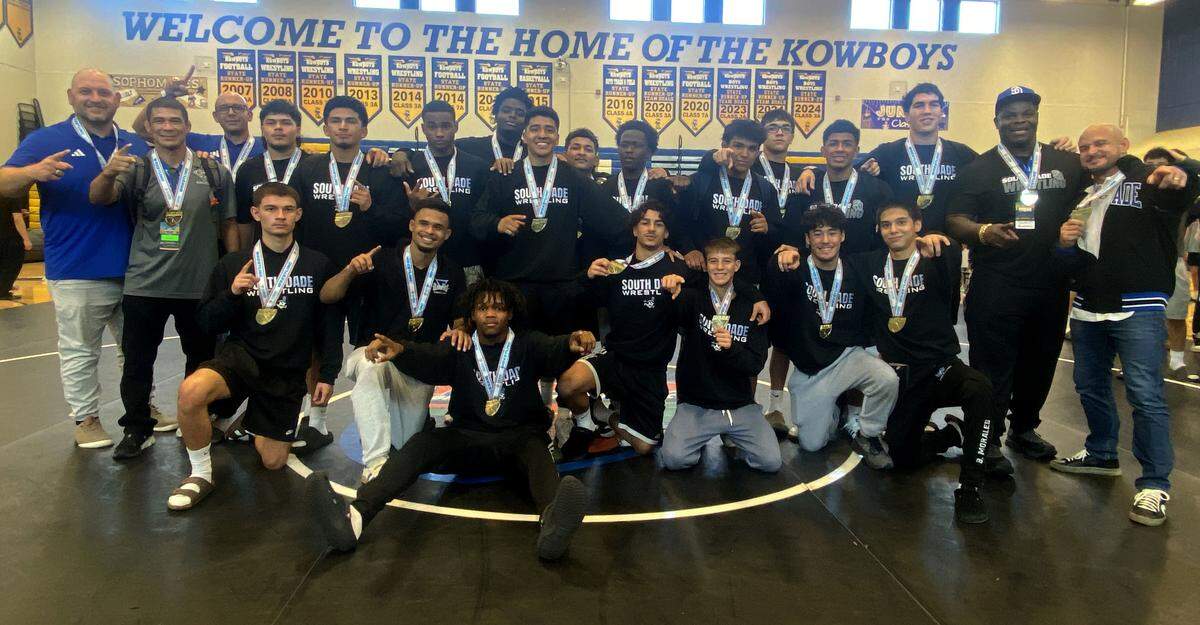 South Dade wrestlers and coaches gather together with the state trophy after winning the Class 3A Duals wrestling state championship on Saturday at Osceola High School in Kissimmee.