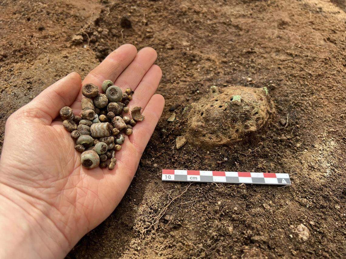 A handful of jewelry beads and an unknown artifact.