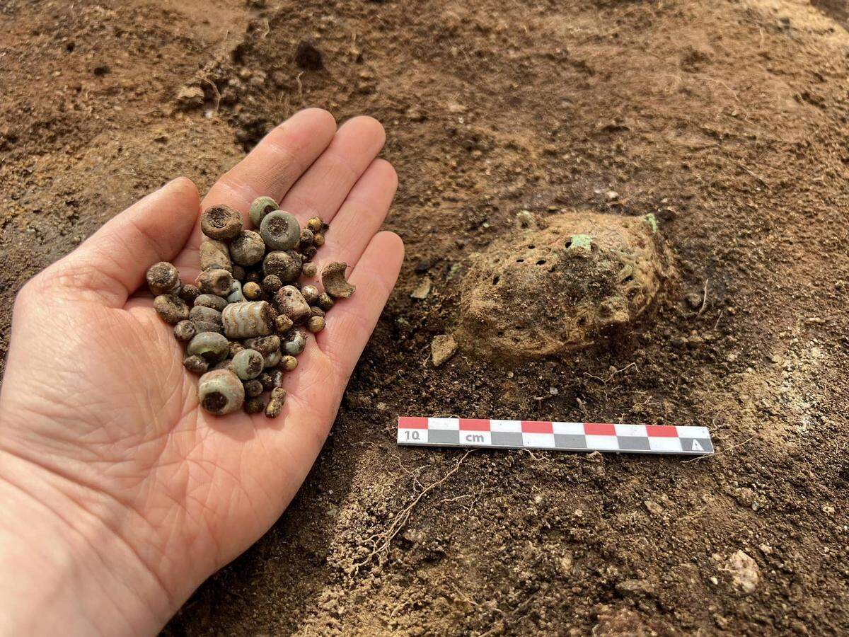 A handful of jewelry beads and an unknown artifact.