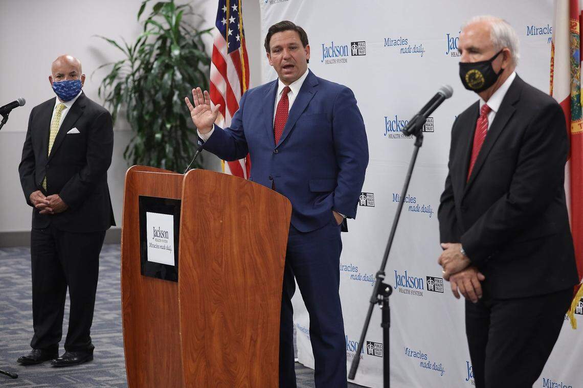 Flanked by Jackson Health System President and CEO Carlos Migoya, left, and Miami-Dade County Mayor Carlos Gimenez, right, Gov. Ron DeSantis answers question during a press conference regarding COVID-19 at Jackson Memorial Hospital in Miami, Florida, on Monday, July 13, 2020.