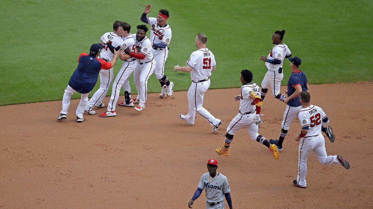 Atlanta Braves’ Max Fried, third from top left, is mobbed after making the game winning hit against the Miami Marlins during the tenth inning of a baseball game Sunday, July 4, 2021, in Atlanta.