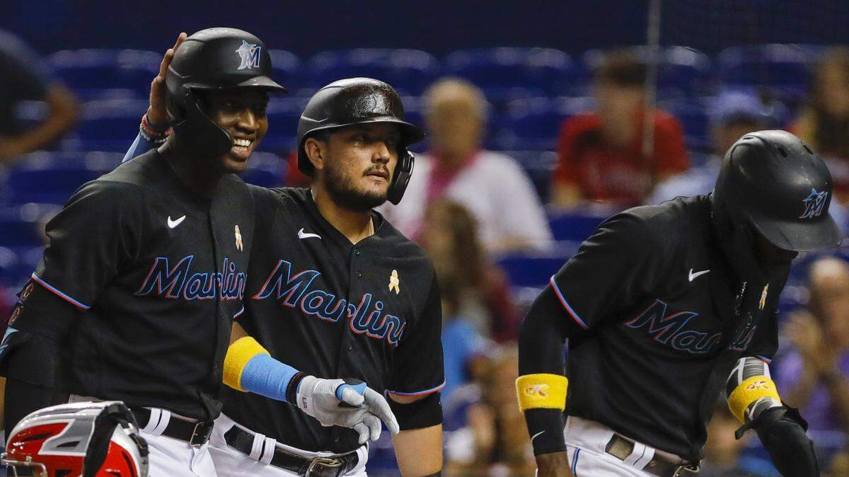 MIAMI, FLORIDA - SEPTEMBER 03: Miguel Rojas #19 of the Miami Marlins (C) celebrates with Jesus Sanchez #76 after scoring during the first inning against the Philadelphia Phillies at loanDepot park on September 03, 2021 in Miami, Florida. (Photo by Sam Navarro/Getty Images)