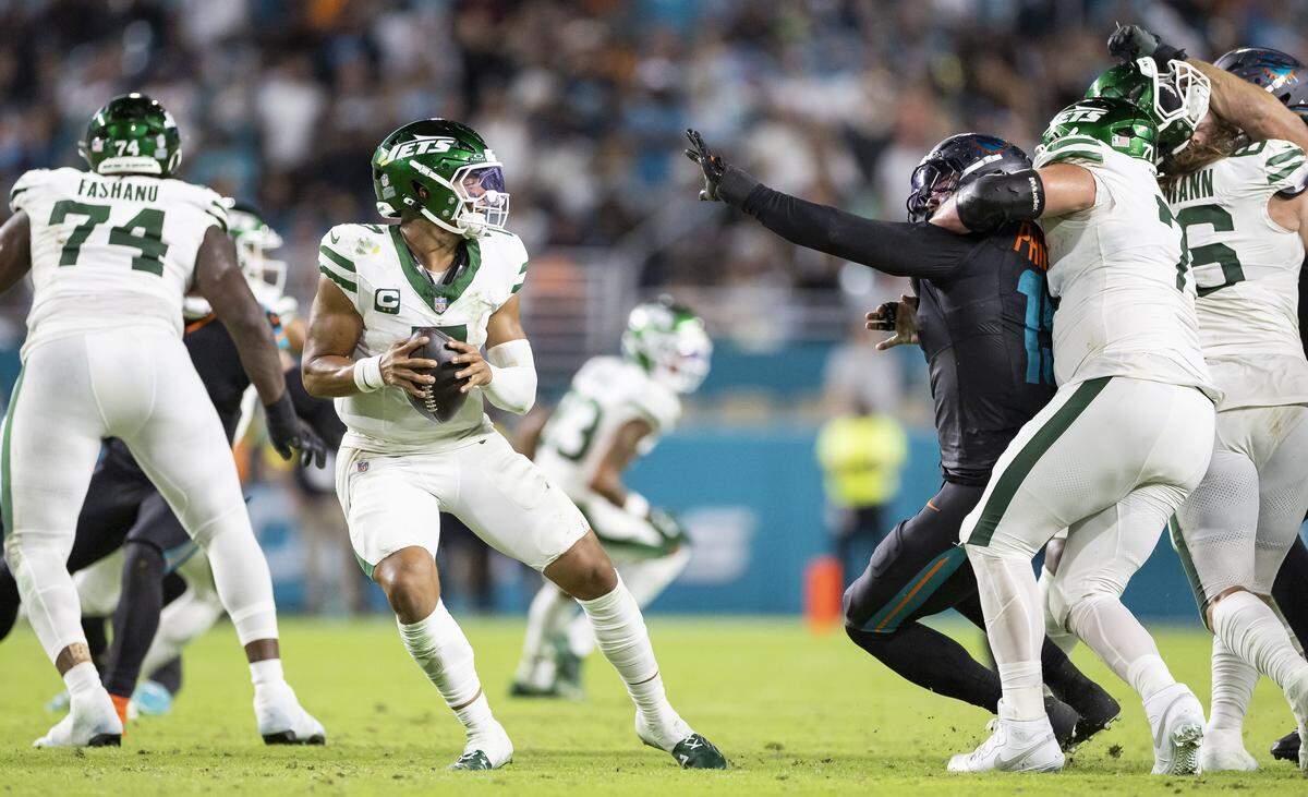 New York Jets quarterback Justin Fields (7) looks to pass the ball as center Josh Myers (71) holds Miami Dolphins linebacker Jaelan Phillips (15) in the second half of their NFL game at Hard Rock Stadium on Monday, Sept. 29, 2025, in Miami Gardens, Fla.
