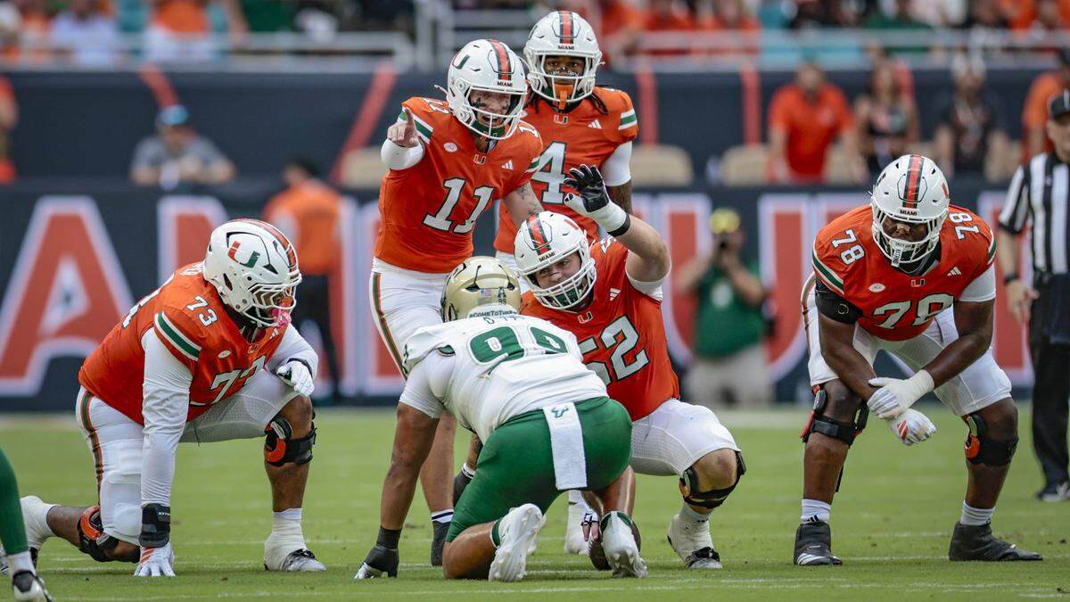 Miami Hurricanes offensive linemen Anez Cooper (73), and Matthew McCoy (78) at the line of scrimmage as James Brockermeyer (52), and quarterback Carson Beck (11) signal while South Florida Bulls defensive tackle Devin Lee (99) linesup in the first half of their NCAA football game at Hard Rock Stadium in Miami Gardens, Florida, on Saturday, September 13, 2025.