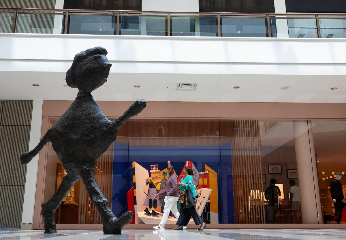 People make their way past ‘Walking Figure,’ a sculpture by Donald Baechler, one of the many art installations available for visitors to see at Aventura Mall on Wednesday, Sept. 25, 2024, in Aventura, Fla.