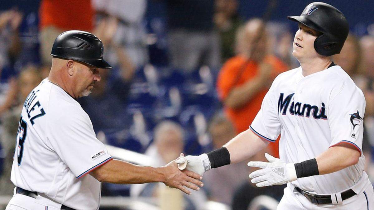 The Miami Marlins’ Garrett Cooper celebrates with third base coach Fredi Gonzalez after hitting a solo home run in the fifth inning against the Milwaukee Brewers on Wednesday, Sept. 11, 2019, at Marlins Park.
