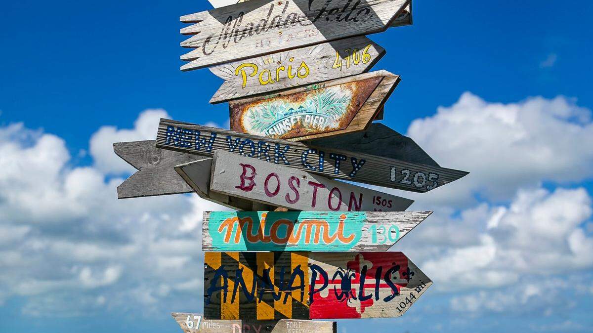 A signpost points to various locations from Sunset Pier in Key West, Florida on Saturday, December 11, 2021.