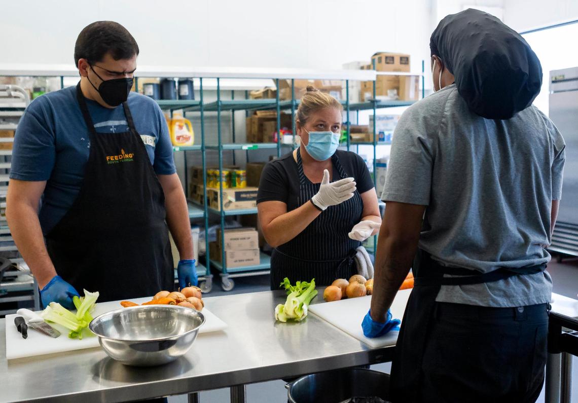 General Manager of Feeding Palm Beach County Chrissy Benoit, 51, center, trains Emilio Rodriguez, 23, left, and Kenny Lawrence, 32, as they participate in Feeding South Florida’s culinary training program in Boynton Beach, Florida on May 5, 2021.