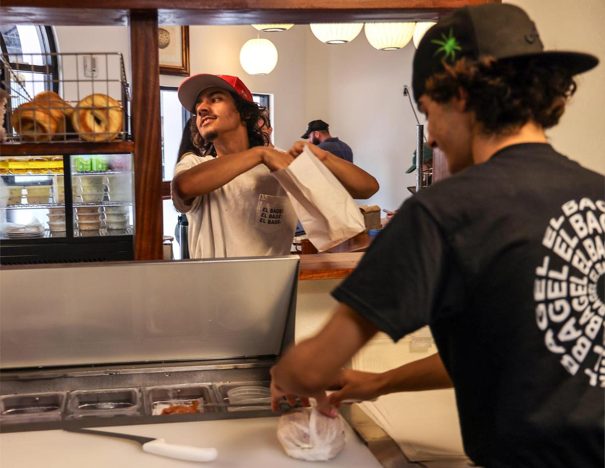 Kitchen manager Danny Padron, 20, left, works out a take-out order with help from line cook Lucas Diaz, 20, right, at the new El Bagel.