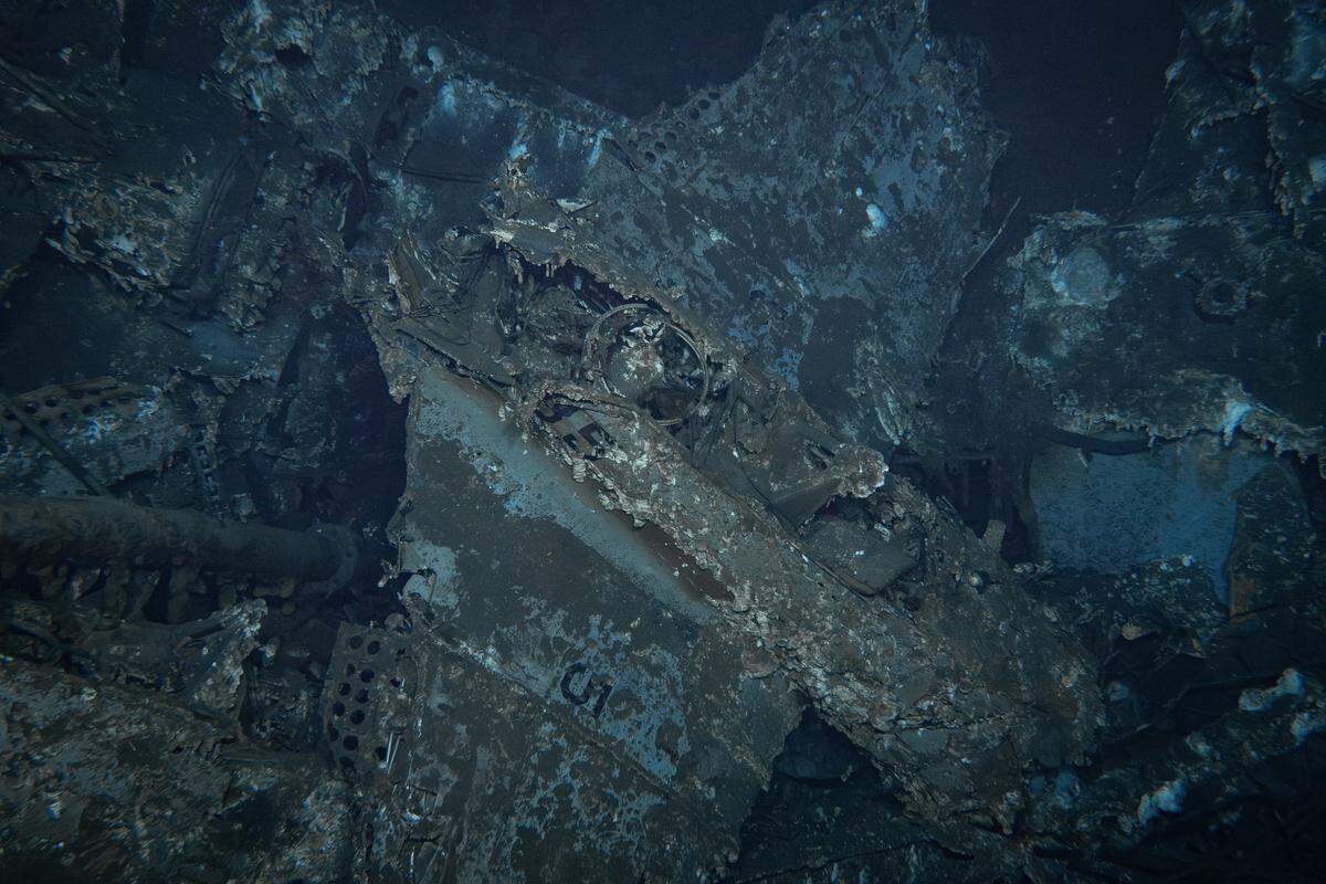 This is the wreckage of a Douglas SBD Dauntless dive bomber with legible markings “B5” on the fuselage beneath the gunner’s ring mount (center of frame) and another “5” visible on the upper surface of the right wing (bottom). It is currently believed this plane is one of two battle-damaged planes from USS Enterprise’s Bombing Squadron Six that landed aboard Yorktown following their attack on the Japanese carrier Kaga.