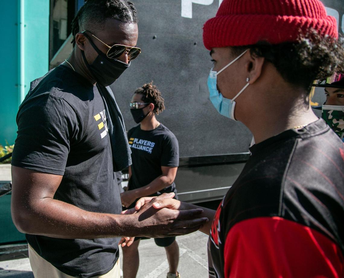 Marlins player Lewis Brinson (left) greets high school baseball player Staling Zabala at Gibson Park in Overtown during a visit by the Players Alliance while on their Pull Up Neighbor Tour on Jan. 5, 2021.