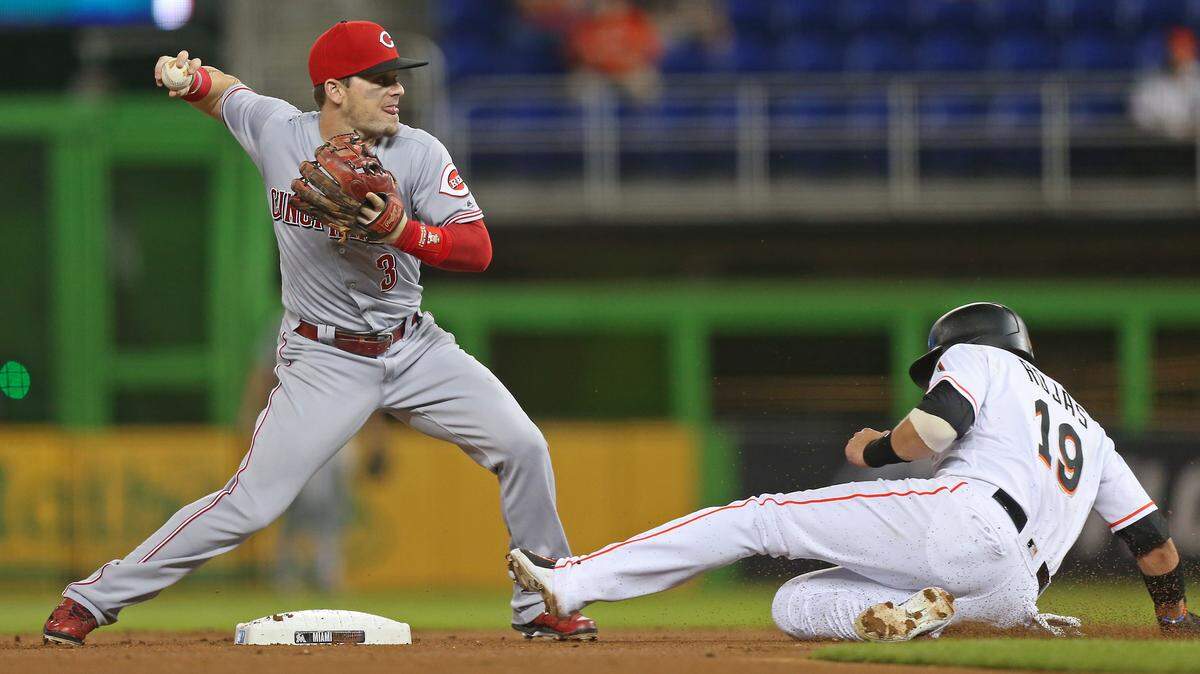 Miami Marlins third baseman Miguel Rojas slides into second base as Cincinnati Reds second baseman Scooter Gennett throws to first base unable to complete a double play during the first inning of a Major League Baseball game at Marlins Park on Thursday, September 20, 2018 in Miami.