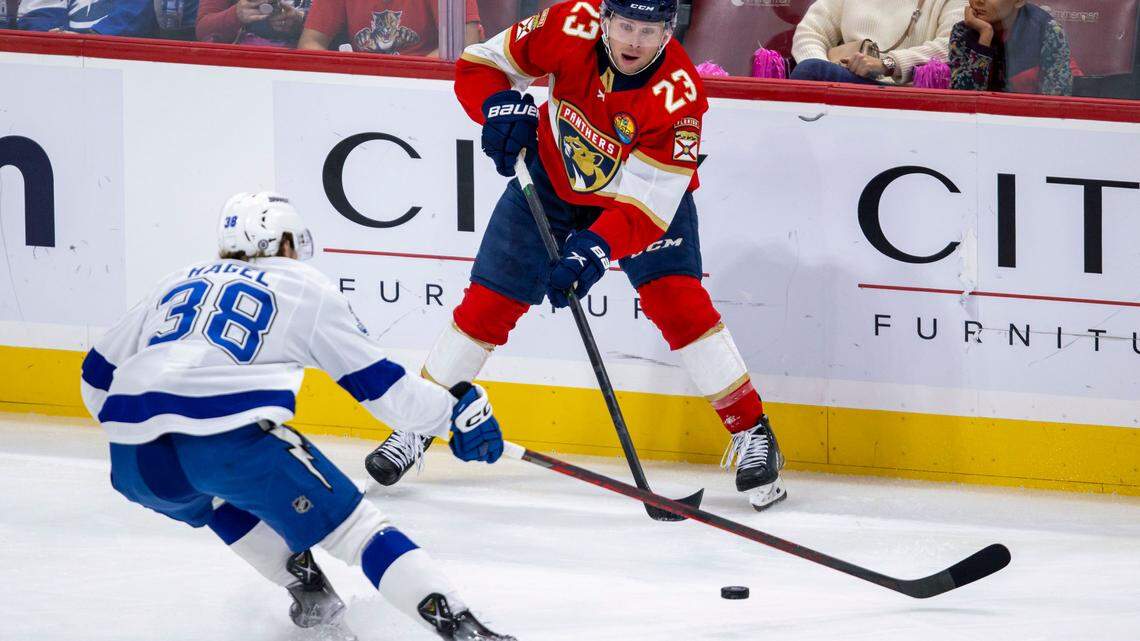 Florida Panthers center Carter Verhaeghe (23) passes the puck past Tampa Bay Lightning left wing Brandon Hagel (38) during the second period of an NHL game at FLA Live Arena in Sunrise, Florida, on Friday, October 21, 2022.