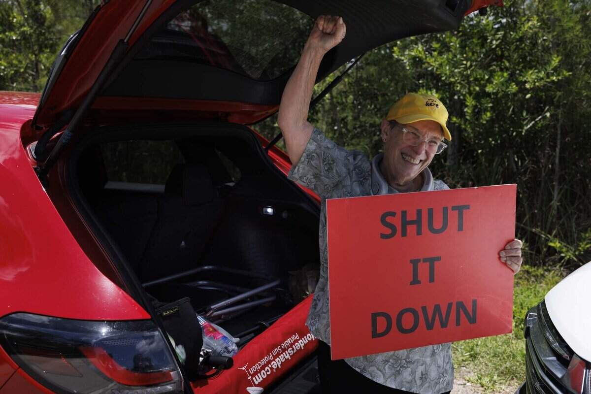 Debbie Wehking, quien ha estado protestando dos o tres veces por semana desde el 3 de julio de 2025, reacciona a una conferencia de prensa con el gobernador Ron DeSantis sobre el cierre de Alligator Alcatraz el jueves 25 de junio de 2026, en Alligator Alcatraz, en Ochopee, Fl. “Supongo que ya no necesito mi cartel,” dijo.