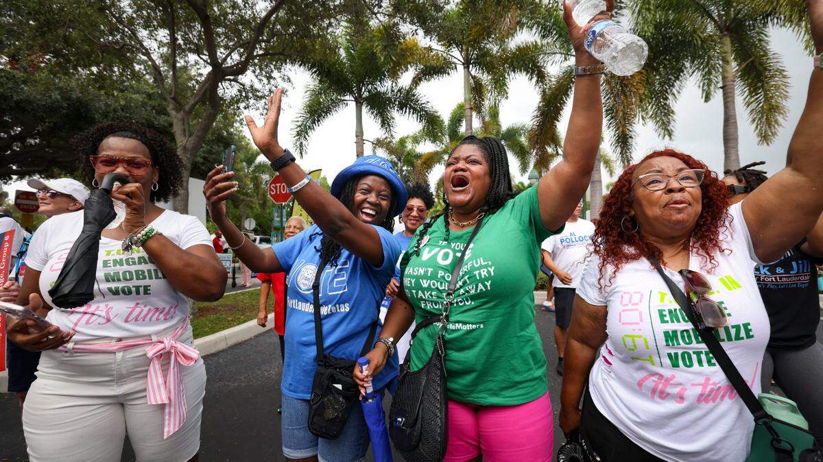 Danette Gipson, in blue, Dr. Mary Smith, in green, and Sharonda Striggles, right, cheer during the Souls to the Polls march to the African American Research Library and Cultural Center on Sunday, Aug. 18, 2024, in Fort Lauderdale, Fla.