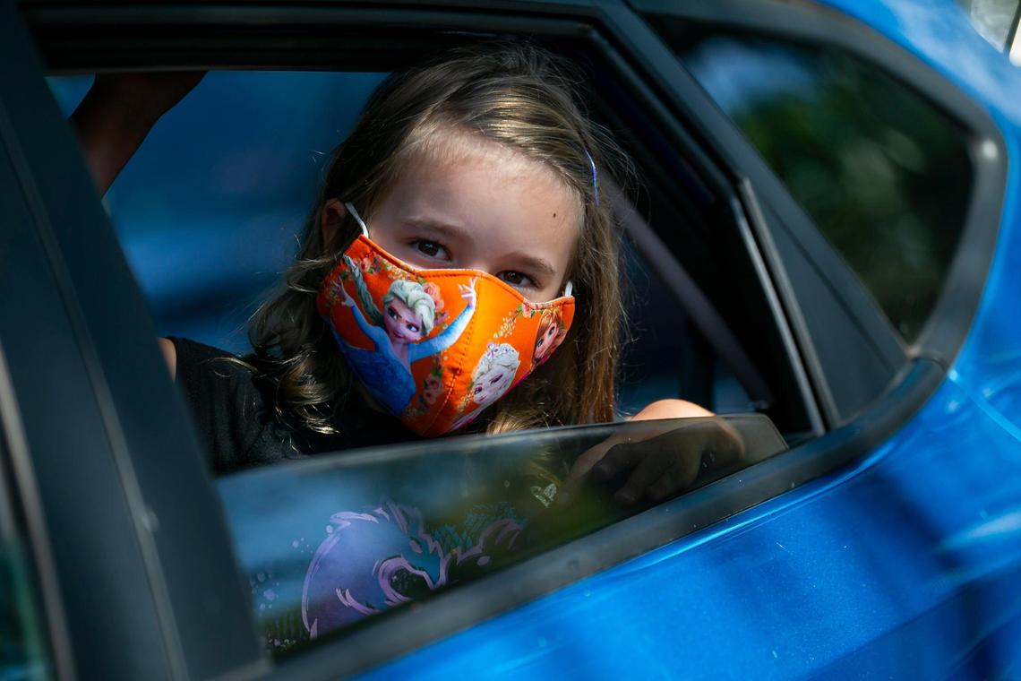 Lily Sherwood, 5, attends a drive-thru distribution event at Joseph C. Carter Park in Fort Lauderdale, Florida on Saturday, Aug. 8, 2020. Volunteers distributed food, sanitation items, backpacks and back-to-school necessities during the Eighth Annual Sunshine Health Orange Bowl Family, Fun & Fit Day drive-thru only event.