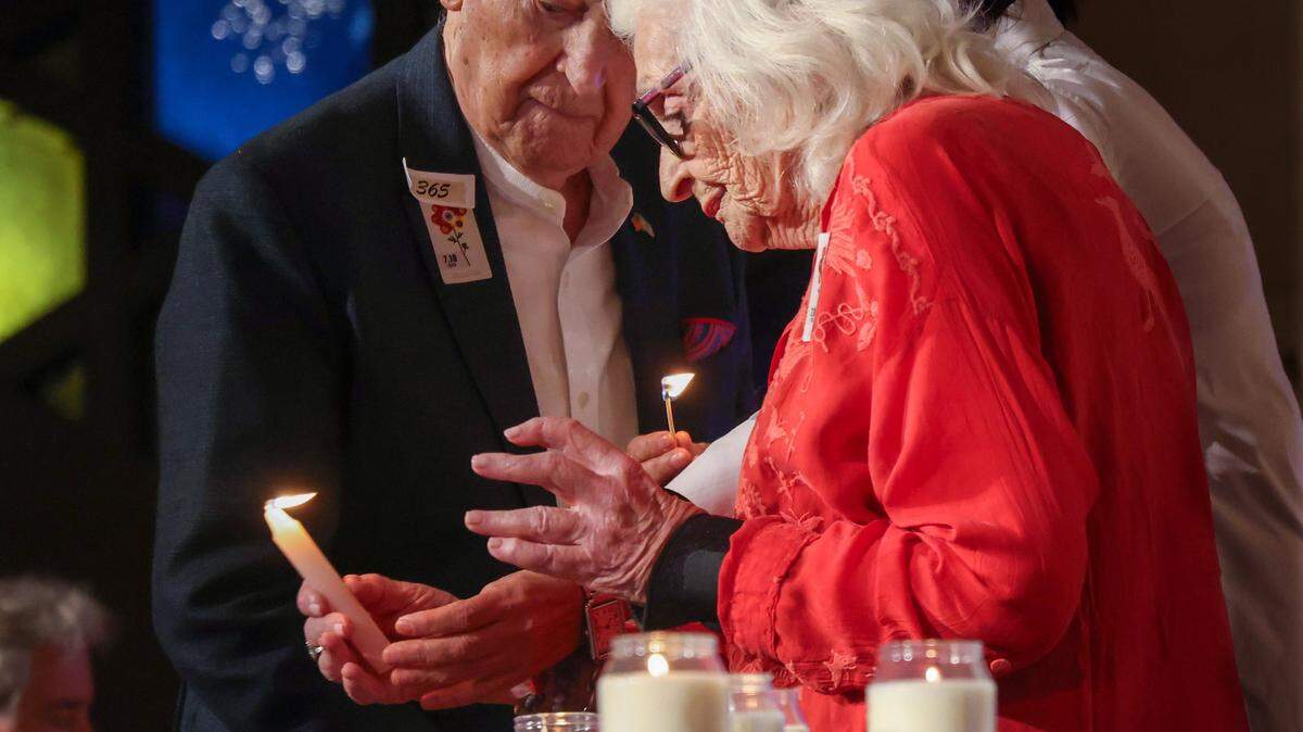 The late David Schechter, left, and holocaust survivor Dr. Miriam Klein Kassenoff, right, lit candles during the moment of silence for victims of the October 7 massacre. Last year, the Greater Miami Jewish community gathered at Temple Beth Sholom in remembrance of the tragic day. 