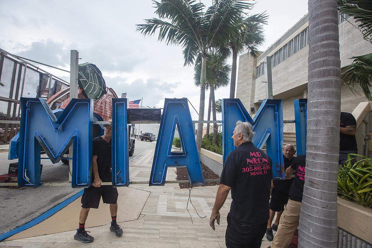 Steve Carpenter, famously known as “Mr. Neon” (right/front), collaborates with Joe Holley (left/back) and Hubert Santos (right/back) on the Big Orange installation, a cherished part of Miami’s NYE tradition, on Friday, December 27, 2024, at the InterContinental Hotel in Downtown Miami.