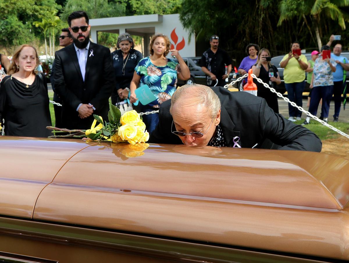 Willie Acosta, longtime personal assistant of astrologer Walter Mercado, places some flowers and kisses Mercado’s casket during the burial ceremony in Cupey in Puerto Rico on Friday, Nov. 8, 2019.