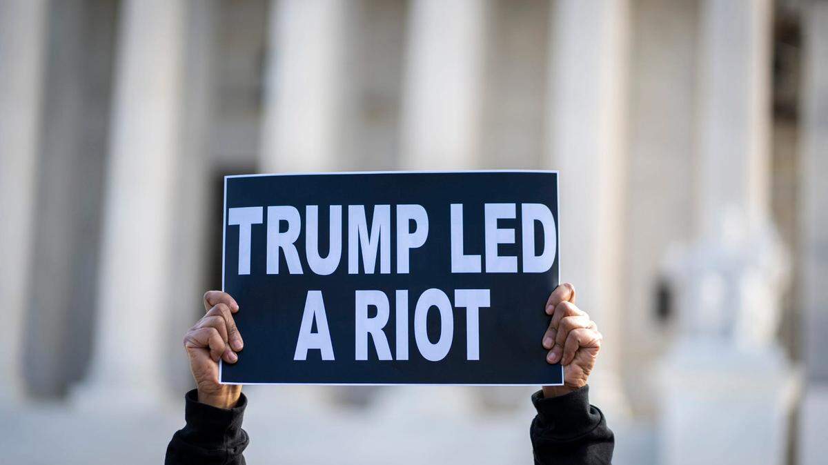 Valarie Walker of New York City raises her sign as protestors gather outside the U.S. Supreme Court as the court reviews a ruling by a Colorado court that barred former President Donald Trump from appearing on the state’s Republican primary ballot due to his role in the Jan. 6, 2021 attacks on the U.S. Capitol.