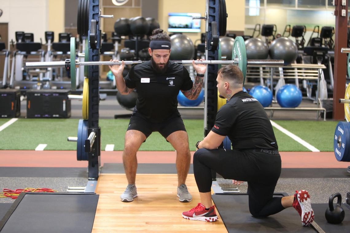24 Hour Fitness Master Trainer, Orlando Lopez, guides Jessie Rodriguez, a Fitness Manager, through a barbell squat as the two demonstrate the exercise at the new fitness center at 1970 NW 117th Pl. in Miami on January 31, 2020.