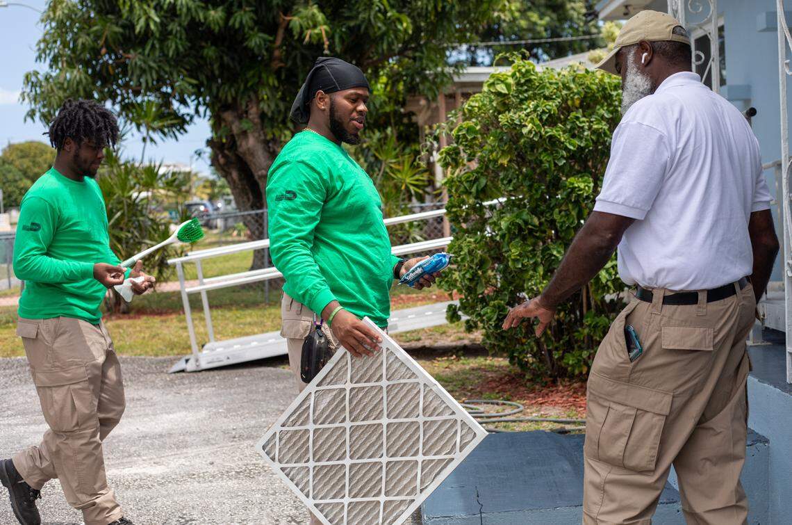 Members of the Greater Miami Service Corps “green corps” clean an air filter at a residents home. The home energy efficiency projects can save residents up to $200 a year on their power bill.