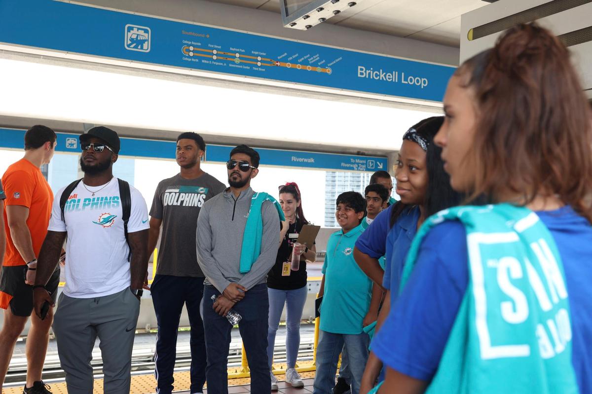 Members of the Miami Dolphins rookie class, left, participate in a historic walking tour of Downtown Miami with local community groups like students from Miami Police Athletic League, right, on Wednesday, June 15, 2022, beginning with tour leaders at the History Miami Museum.